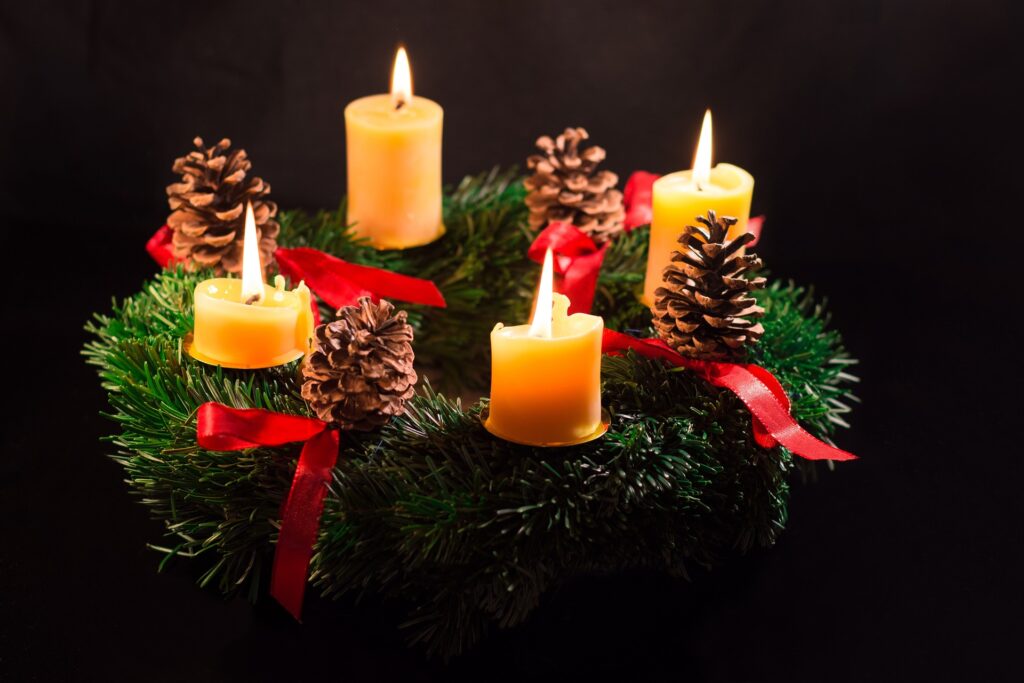 Advent wreath with four lighted candles and pine cones