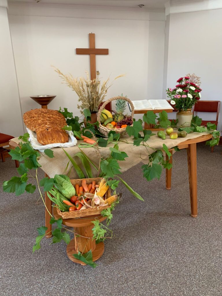 Church decorated for harvest festival with fruit, vegetables, bread and flowers on the altar