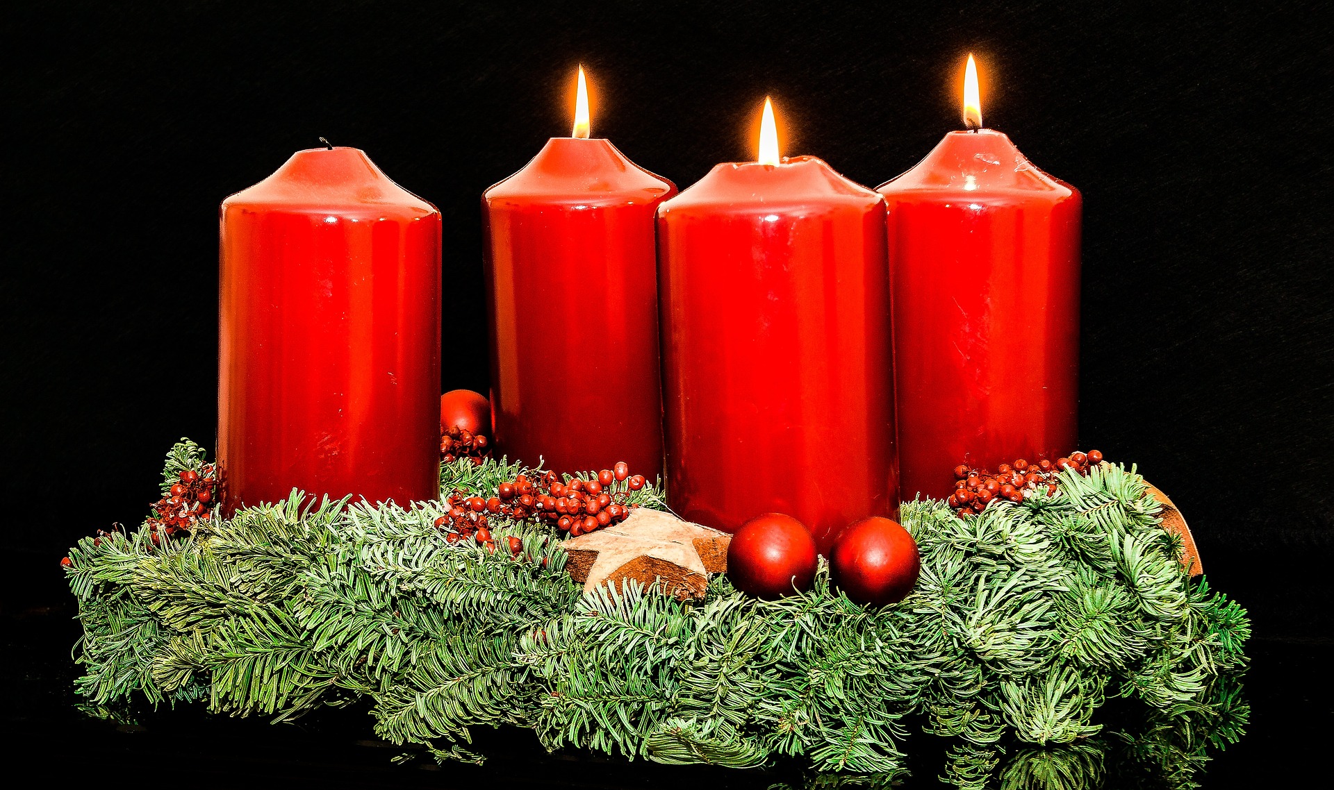Advent wreath with four red candles. Only three of the candles are burning.